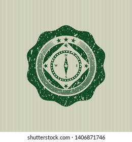 Green compass icon inside distressed rubber stamp with grunge texture