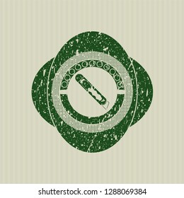 Green cutter icon inside distressed rubber stamp with grunge texture