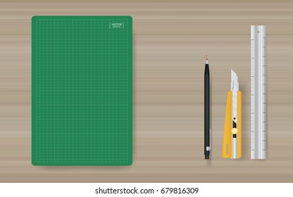 Green cutting mat with office object set - ruler, cutter and pencil on wood background. Vector illustration.