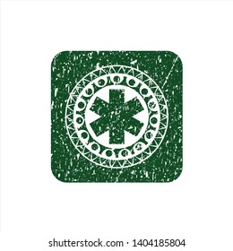 Green emergency cross icon inside rubber seal with grunge texture