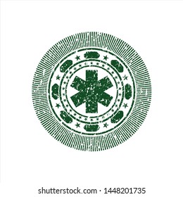 Green emergency cross icon inside distressed rubber grunge seal