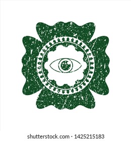 Green eye icon inside distress rubber stamp with grunge texture