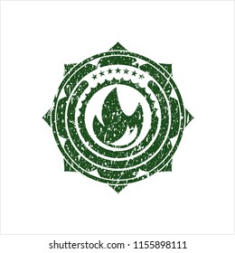 Green fire icon inside distress rubber seal with grunge texture
