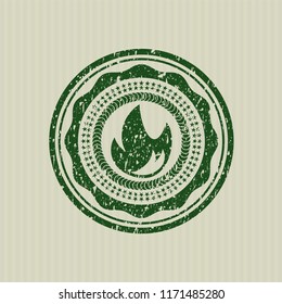 Green fire icon inside distress rubber stamp with grunge texture