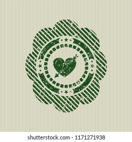 Green heart with arrow icon inside rubber seal with grunge texture
