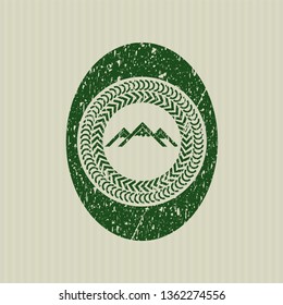 Green mountain icon inside distressed rubber seal