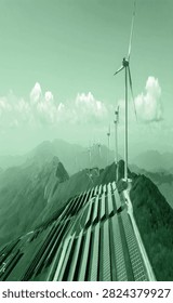 Green mountain landscape featuring a long row of power transmission poles and electric wires extending into the distance under cloudy skies. Ideal for energy infrastructure, ecology, and utility concepts.