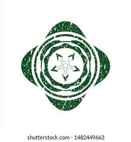 Green ninja star icon inside distress rubber seal with grunge texture