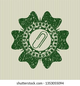 Green paper clip icon inside distressed rubber stamp with grunge texture