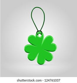 Green plastic shamrock leaf tag on a rope loop over green background