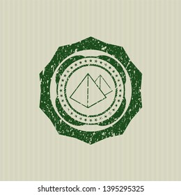 Green pyramids icon inside distressed rubber texture