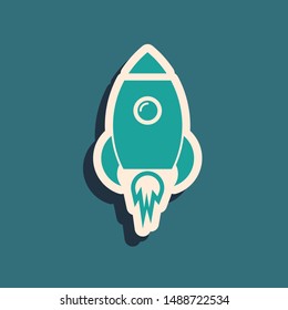Green Rocket ship with fire icon isolated on blue background. Space travel. Long shadow style. Vector Illustration