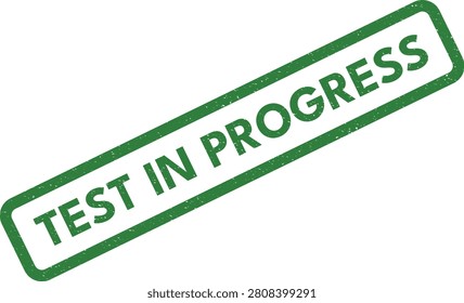 A green rubber stamp displaying the phrase 'TEST IN PROGRESS,' signifying that an examination, experiment, or procedure is currently underway.