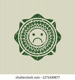 Green sad face icon inside distressed rubber seal