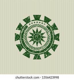 Green sun icon inside distressed rubber seal with grunge texture
