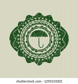 Green umbrella icon inside rubber stamp with grunge texture