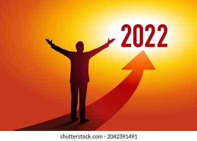 Greeting card 2022 showing a businessman opening his arms in front of a red arrow towards a sunny horizon, symbol of hope and success for the new year.