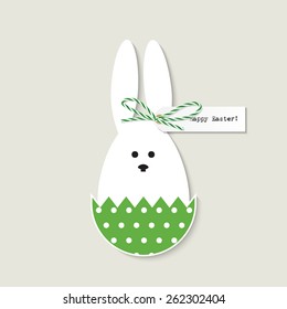 Greeting card with easter bunny sitting in green polka dot easter egg shell