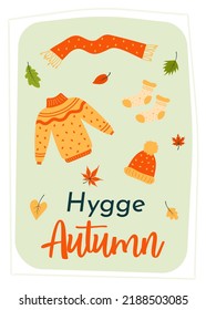 Greeting card with knitted sweater, scarf, hat, socks and autumn leaves. Hygge autumn quote. Print as a card or a cozy poster. Autumn, harvest festival, thanksgiving day, cozy season concept.