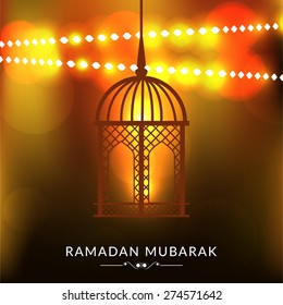 A greeting card template- 'Ramadan Kareem' with Arabic lamp or lantern on shiny golden background