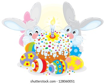 Grey bunnies with a colorfully decorated Easter cake and painted eggs