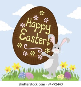 Grey Easter Bunny carrying a huge chocolate Easter Egg with "Happy Easter" iced on it.