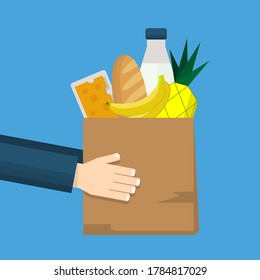 Grocery store and food delivery with hands holding a paper shopping bag full of goods and product including bread, milk, banana, pineapple and cheese. Delivery service to door