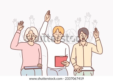 Group of people raise hands sitting in conference room and participating in business training from well-known guru. Men and women raise hands with smile to vote for joint decision.