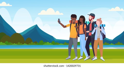 group tourists hikers with backpacks taking selfie photo on smartphone camera hiking concept mix race travelers on hike river mountains landscape background flat full length horizontal
