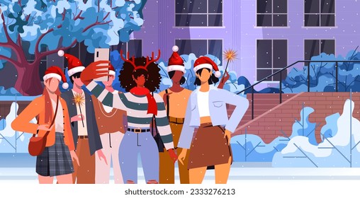 Group of young modern friends in Christmas hats celebrate Christmas and New Year. Different people make a joint photo portrait on a phone camera, on a snowy street with falling snow.