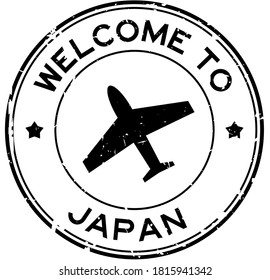 Grunge black welcome to Japan word with airplane icon round rubber seal stamp on white background