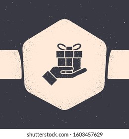 Grunge Gift box in hand icon isolated on grey background. Merry Christmas and Happy New Year. Monochrome vintage drawing. Vector Illustration