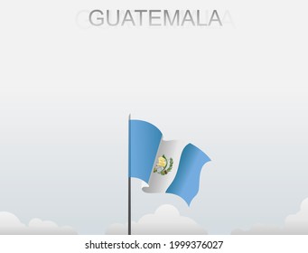 The Guatemalan flag flutters on a pole that stands tall under a white sky