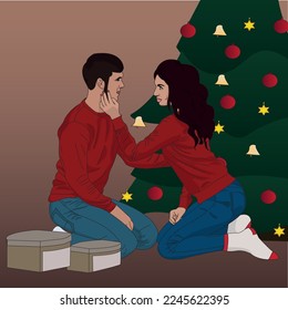 
A guy and a girl in love are sitting on their knees in New Year's sweaters against the backdrop of a Christmas tree and gifts. New Year's atmosphere in the family.