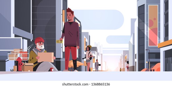 guy giving money poor man sitting floor with belongings in trolley cart begging for help beggar holding sign board homeless concept modern city street sunset cityscape background horizontal