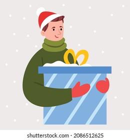 The guy in the santa hat is holding a big gift. New Year's mood. Winter clothes. Shopping before Christmas.