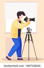 The guy standing and adjusting the lens. Photographic art. A cameraman prepares camera for a photo shoot. Photographer with camera takes picture in the photo studio with the white background