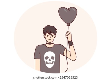 Chico adolescente en ropa gótica sostiene globo negro en forma de corazón para la chica que le gusta de la escuela. Chico sin emociones en camiseta negra con calavera es fan de la asociación informal de la subcultura gótica