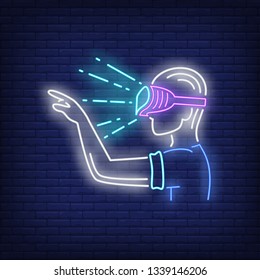 Guy wearing VR goggles neon sign. Man in VR glasses pointing finger on brick wall background. Vector illustration in neon style for billboards, banners, VR headset