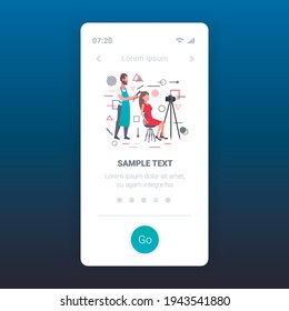 hairdresser blogger making hairstyle cutting hair tips of woman customer in beauty salon man recording online video with camera on tripod blogging concept full length mobile app copy space