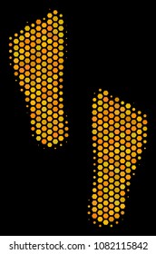 Halftone hexagonal Human Footprints icon. Bright gold pictogram with honeycomb geometric pattern on a black background. Vector pattern of human footprints icon composed of hexagon dots.