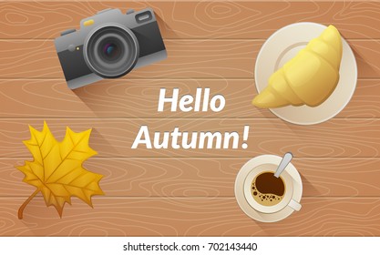 Hallo autumn text. Tasty buttery croissant and cup and camera of hot coffee on old wooden table with yellow leaves. Vector flat illustration