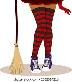 Halloween close up witch legs wearing red and black stockings holding broom