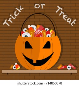 Halloween pumpkin bucket with candies on brick walls 