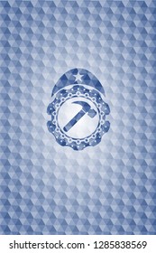 hammer icon inside blue emblem or badge with abstract geometric pattern background.