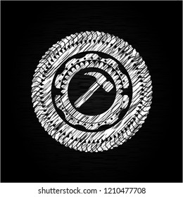 hammer icon inside chalkboard emblem on black board