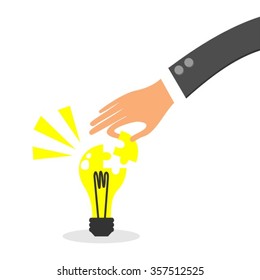 Hand of Business Man Adding A Puzzle Piece to an Idea Light bulb