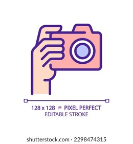 Hand with camera pixel perfect RGB color icon. Person taking shot with analog equipment. Photographer tool. Isolated vector illustration. Simple filled line drawing. Editable stroke