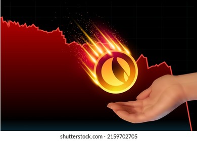 Hand catches a falling coin. Terra token cryptocurrency. Currency on blockchain stock market with red line pointing down. 