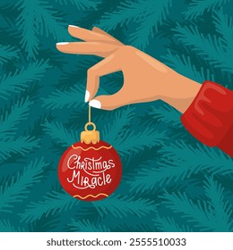 A hand decorating a Christmas tree, holding an ornament. Christmas ball. Tree branches background